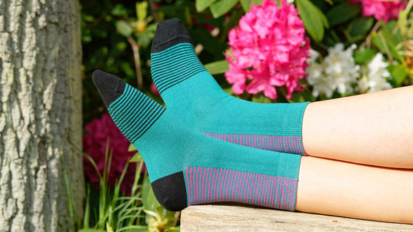 Woman wearing teal Anne ladies luxury socks with flowers in the background