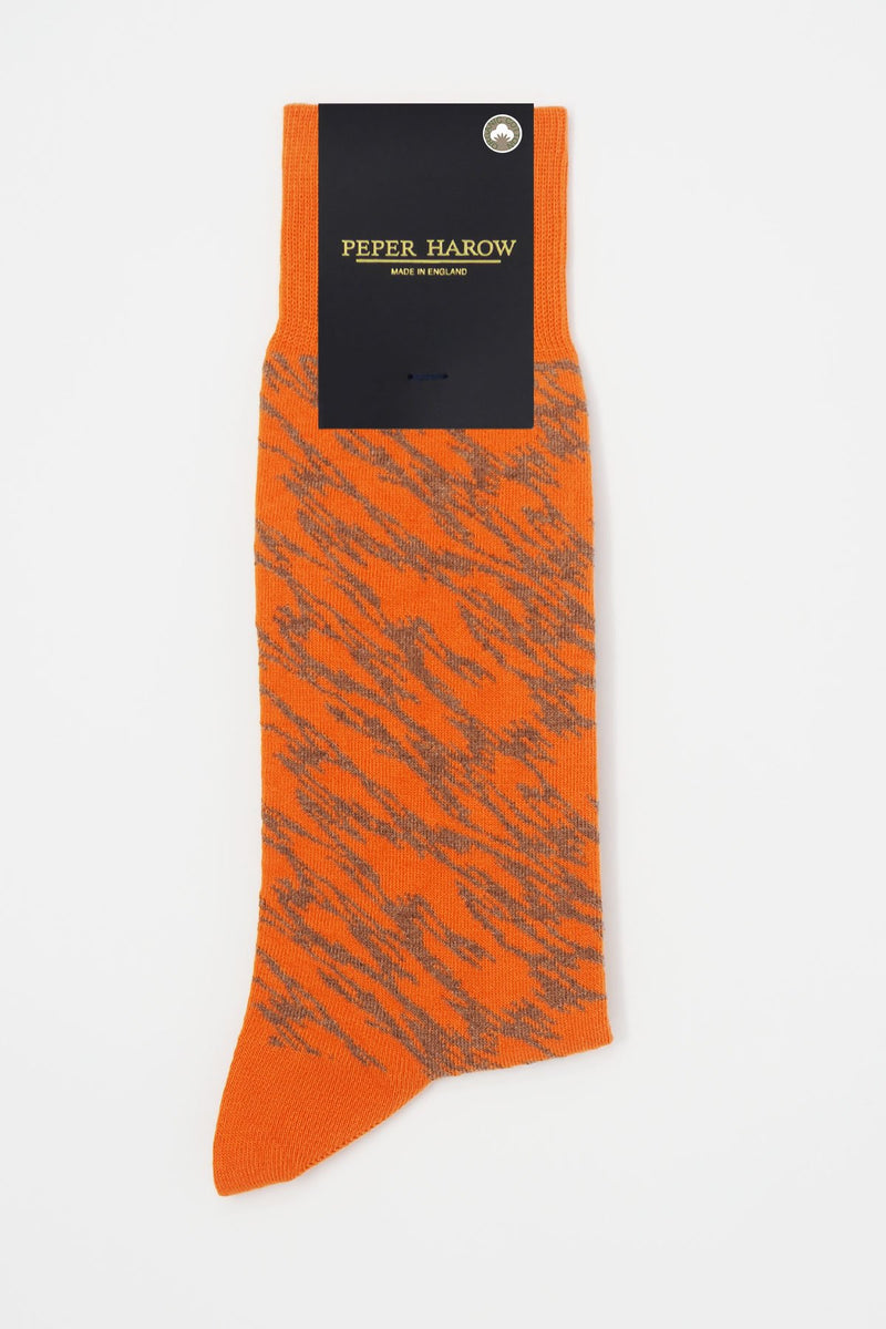 Pandemonium orange men's luxury socks by Peper Harow, featuring a quirky brown pattern and brown toe and heel in packaging.