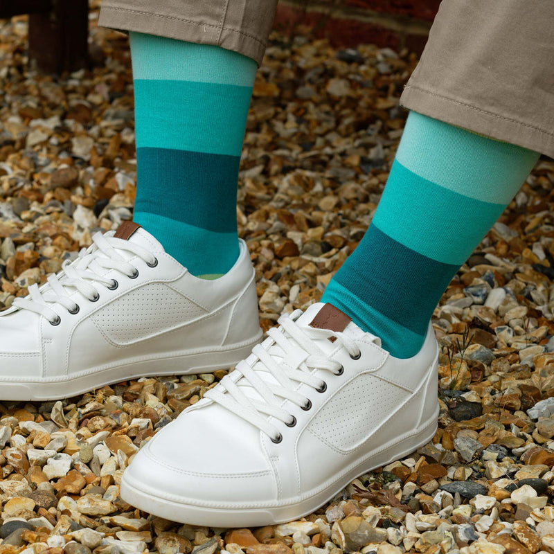 Man sitting outside wearing tan trousers, white trainers and earth Block Stripe men's luxury socks from Peper Harow