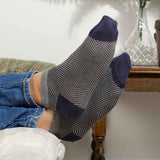 Man with his feet up on the couch wearing grey Lux Taylor men's luxury trainer socks