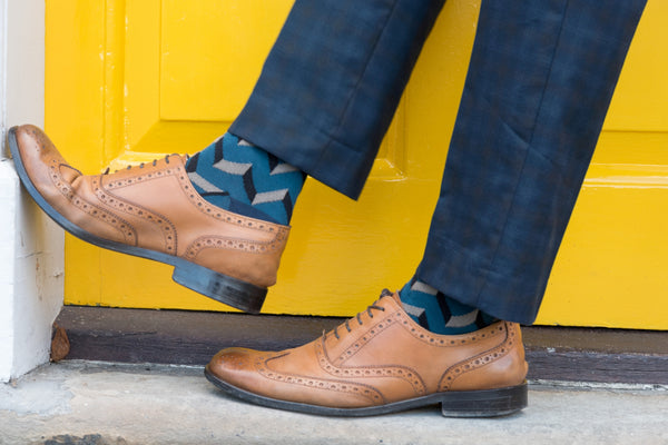 Man wearing smart shoes and Peper Harow luxury Supima cotton socks in a doorway with a yellow door