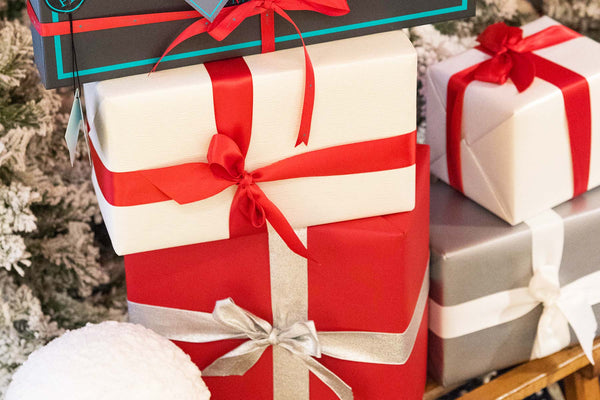 Neatly wrapped gifts and a Peper Harow gift box with ribbon on under a Christmas tree.