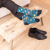 men sitting on the couch wearing green royal flush socks black shoes