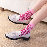 woman wearing pink leopard socks with white smart shoes at home on the couch luxury comfort quality