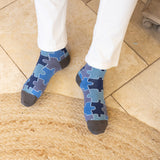 men wearing blue jigsaw socks at home resting his feet in the kitchen