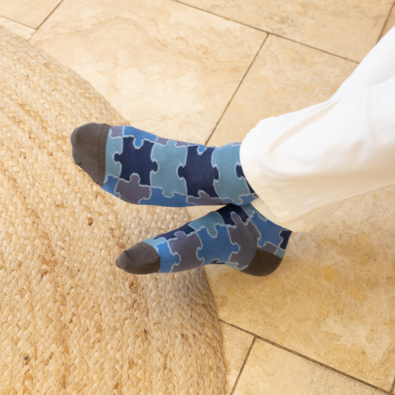 men wearing blue jigsaw socks at home resting his feet in the kitchen
