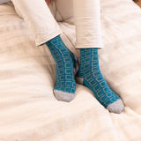men wearing teal cube men's socks laying on the bed beige pants
