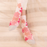 women wearing pink jigsaw socks at home laying on the bed