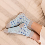 woman wearing blue cube socks at home laying on the bed
