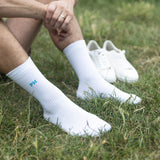 Man sitting in grass wearing Peper Harow white Essentials men's luxury sport socks