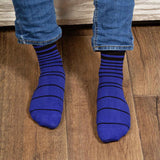 Man sitting on Sofa wearing jeans and black Retro Stripe men's luxury socks by Peper Harow