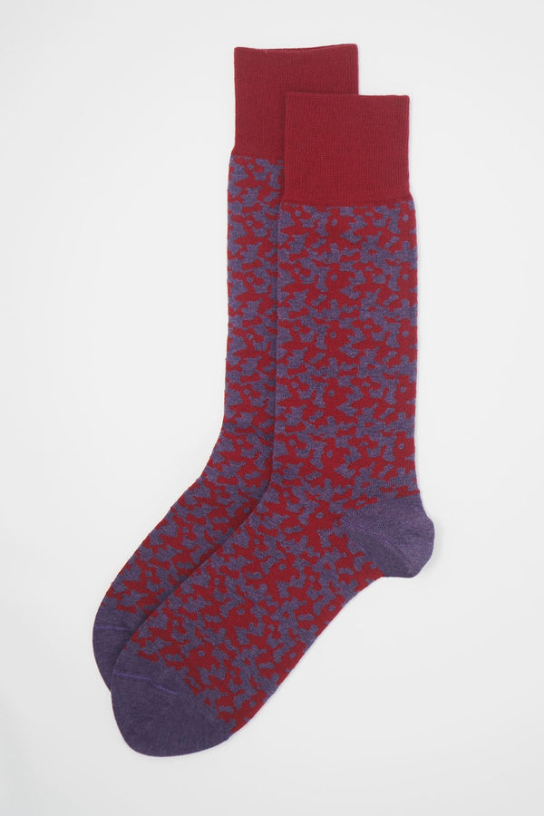 A pair maelstrom red men's luxury socks by Peper Harow, featuring a quirky purple pattern and purple toe and heel.