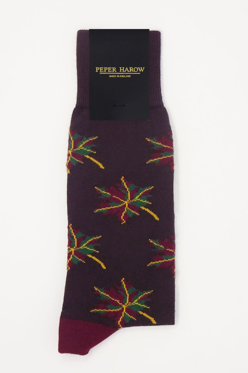A maroon, green and yellow maple leaf on deep wine purple socks with packaging