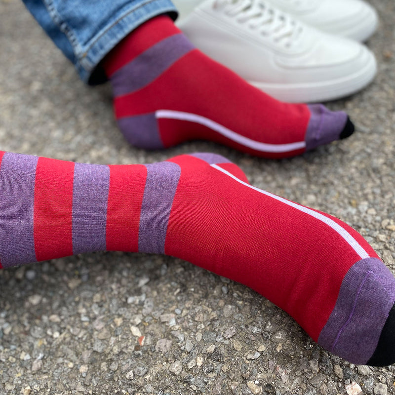 Red equilibrium men's socks featuring a white line along the foot, a purple toe and heel and three purple stripes down the calf