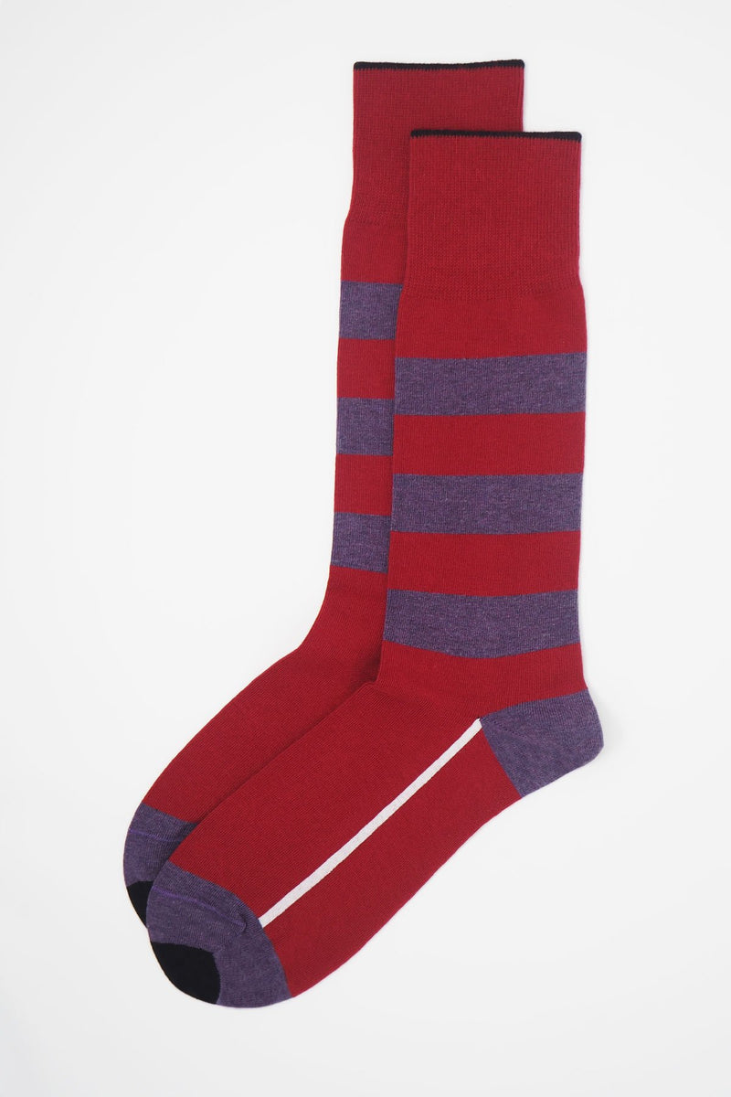 A pair of red equilibrium men's luxury socks by Peper Harow, featuring a white stripe along the foot, and three purple stripes down the calf and on the heel and toe