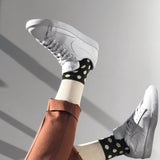 Gentleman with brown trousers and white trainers wearing Cream Mayfair luxury socks by Peper Harow