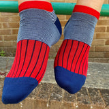 Man wearing Peper Harow scarlet oxford stripe trainer socks sitting on a metal railing