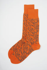 A pair of Pandemonium orange men's luxury socks by Peper Harow, featuring a quirky brown pattern and brown toe and heel.
