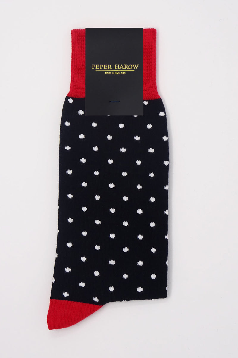 A pair of black pin polka men's socks with white polka dots and a red heel and cuff in packaging