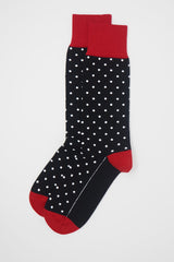 A pair of black pin polka men's socks with white polka dots and a red heel, toe and cuff