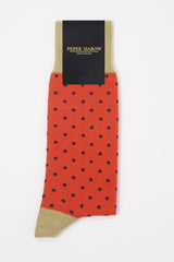 A pair of orange pin polka men's socks with purple polka dots and a beige heel and cuff in packaging