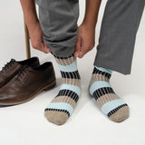Close up of man wearing Peper Harow turquoise Chord men's luxury socks with brown shoes behind