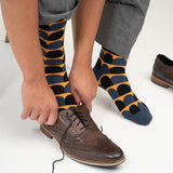 Man putting brown shoes on whilst wearing Peper Harow navy Ouse men's luxury socks