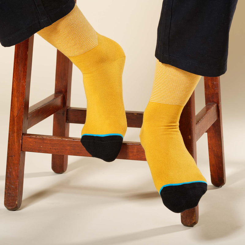 Man sitting on stool wearing amber Chevron men's luxury socks