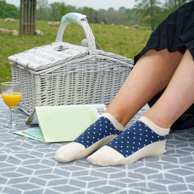 Woman having a picnic in a field wearing Peper Harow beige Organic Polka luxury women's trainer socks