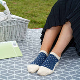 Woman in a black skirt having a picnic in a field wearing Peper Harow beige Organic Polka luxury women's trainer socks