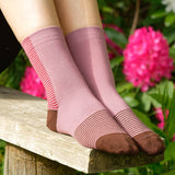 Woman sitting on a bench outside wearing berry Anne ladies luxury socks by Peper Harow