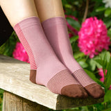 Woman sitting on a bench outside wearing berry Anne ladies luxury socks by Peper Harow