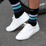 Man standing next to a bicycle wearing white trainers and black Striped Sport organic cotton socks by Peper Harow