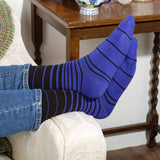 Man with his feet up on the sofa wearing Peper Harow black Retro Stripe men's luxury socks