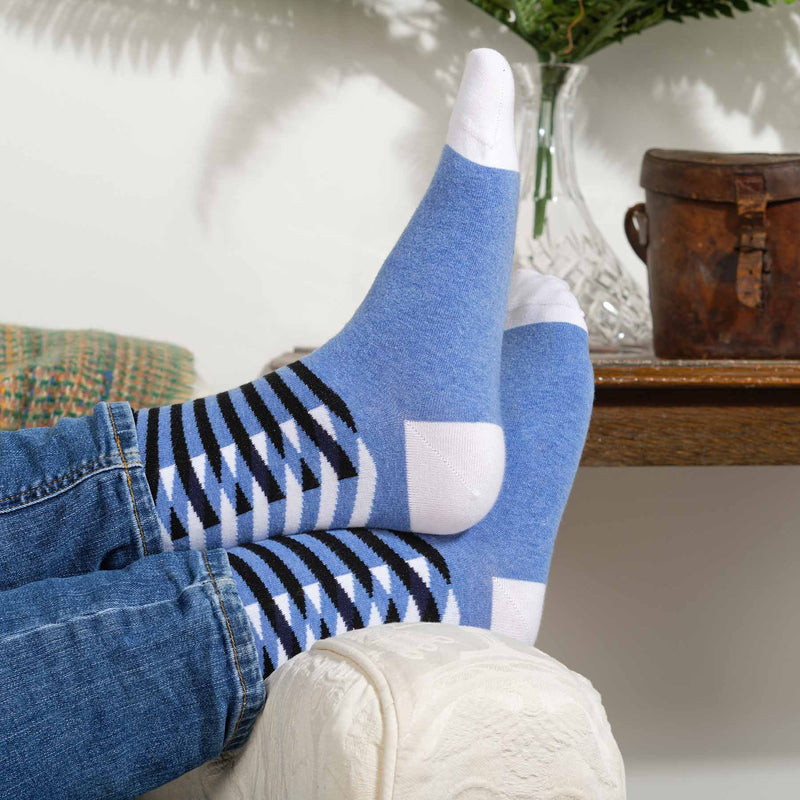 Man laying on sofa wearing jeans and blue Symmetry luxury organic cotton socks by Peper Harow