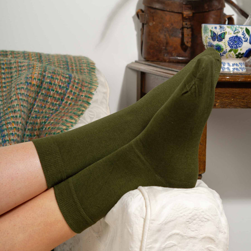 Woman laying on sofa wearing green Classic ladies luxury socks by Peper Harow
