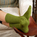 Woman with feet on foot rest wearing green Ribbed women's luxury bed socks