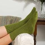 Woman with feet on sofa wearing women's green Ribbed luxury bed socks