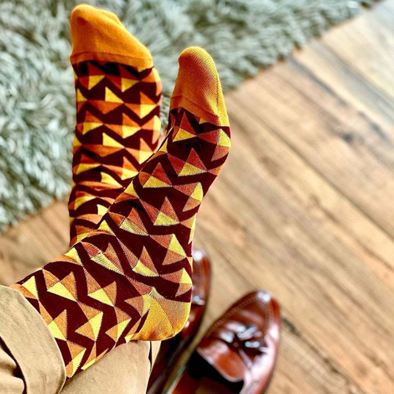 Man sitting on chair wearing maroon Triangle men's luxury socks by Peper Harow