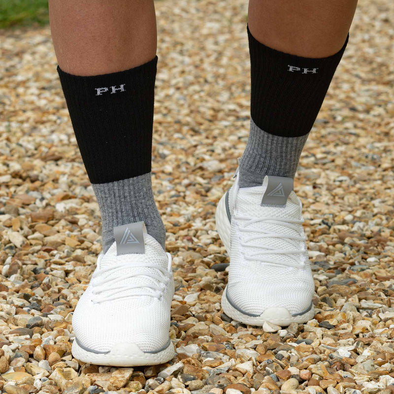 Man wearing white trainers and Peper Harow men's black Recycled cotton sport socks
