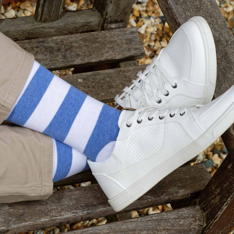 Man with his feet up on a bench wearing white trainers and blue Equilibrium men's luxury socks by Peper Harow
