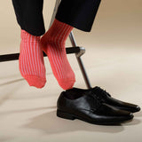 Man sitting on a chair wearing smart trousers and Peper Harow coral Casual Ribbed recycled cotton socks