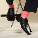 Man wearing smart trousers, smart black shoes and Peper Harow coral Casual Ribbed recycled cotton socks
