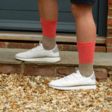 Man wearing white trainers and men's coral Recycled cotton sport socks, standing on stairs.