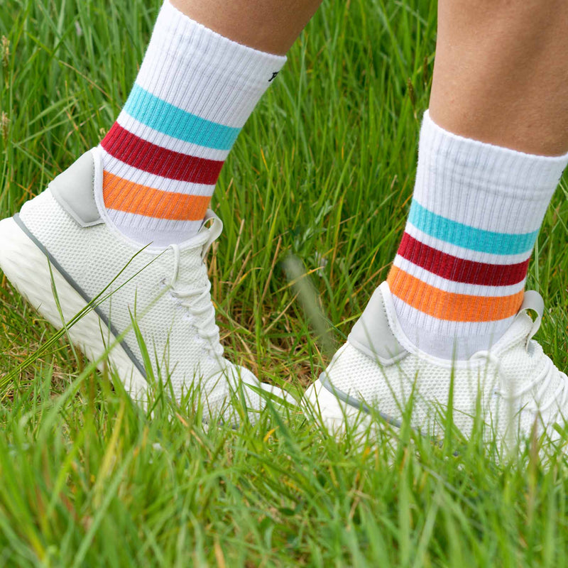 Man walking in grass wearing white trainers and white Striped organic cotton men's luxury sport socks