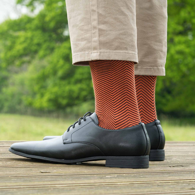 Man wearing tan trousers, black shoes and Peper Harow orange Lux Taylor men's luxury socks