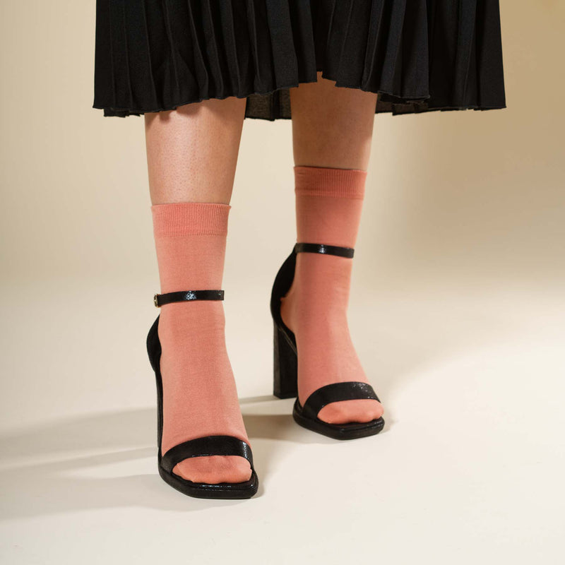 Woman wearing black shoes, a black skirt and Peper Harow peach Classic women's luxury socks