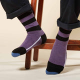 Man sitting on wooden stool wearing purple Equilibrium luxury organic cotton socks by Peper Harow