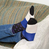 Man laying on a sofa wearing jeans and purple Mayfair men's luxury socks by Peper Harow