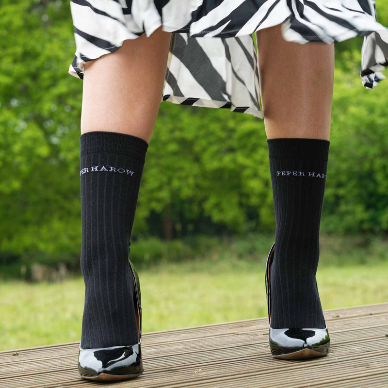 Woman wearing black high heels, zebra print skirt and Peper Harow recycled ribbed women's socks in black